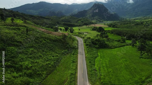 Aerial top view Cinematic aerial drone flight, car running through the green valley in Phayao Province Thailand. photo