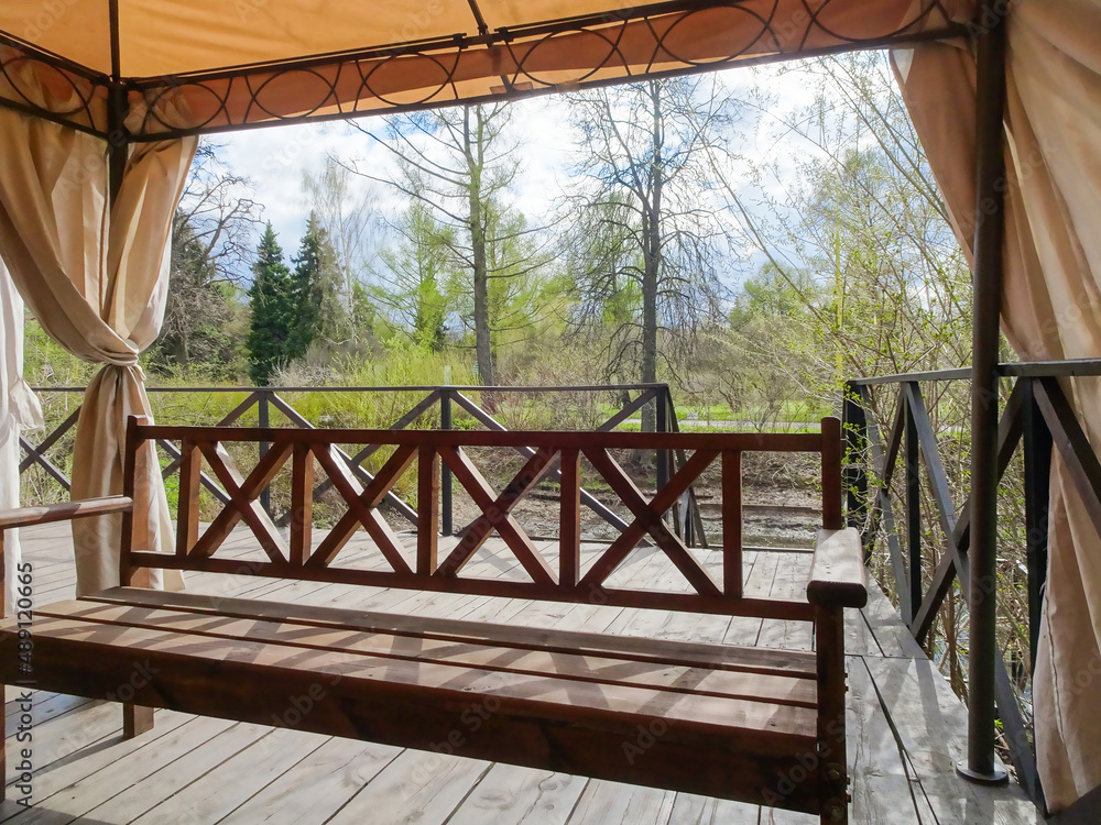 Picnic area with wooden benches and fabric tent, garden pavilion, selective focus