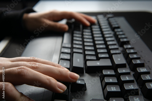 Close up image of woman hands typing on computer keyboard and surfing the internet on table.