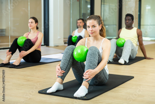 Portrait of young sporty woman during group core training with bender ball at gym. Healthy lifestyle and pilates concept