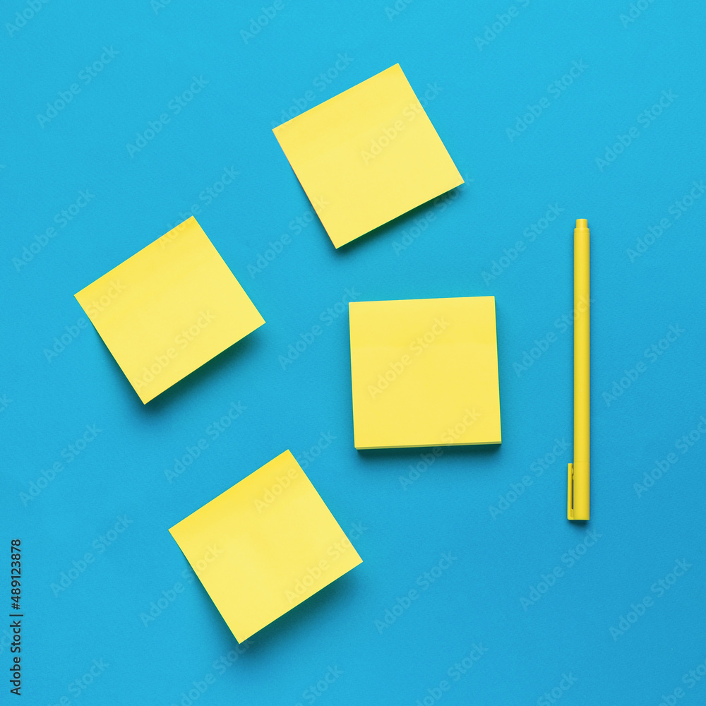 A set of yellow paper notes and a yellow pen on a blue background.