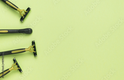 Several black and green razors on a green background. Flat lay.