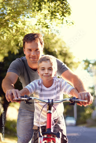 Teaching my boy to ride a bike. Shot of a father and son spending quality time together with a bicycle.