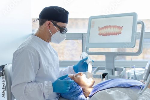 Male dentist performing a scan for the 3d model of a female patient s mouth. Dental clinic concept