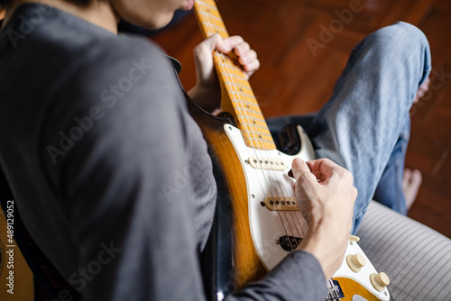 Canvas Print A man playing electric guitar on a bed