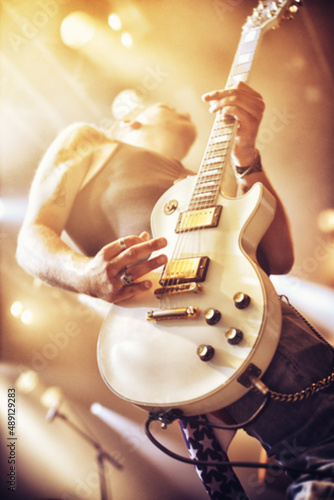 Low angle view of a guitarist on stage at a gig. This concert was created for the sole purpose of this photo shoot, featuring 300 models and 3 live bands. All people in this shoot are model released. photo