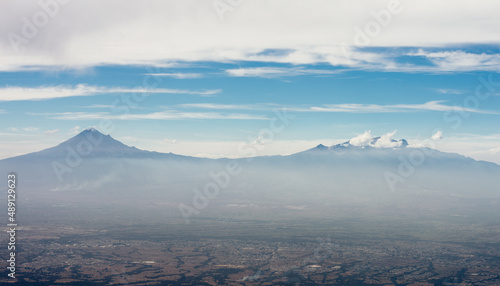 Panoramic view of the popocatepetl and Iztaccihuatl volcanoes during a summer day with cloudy blue sky photo