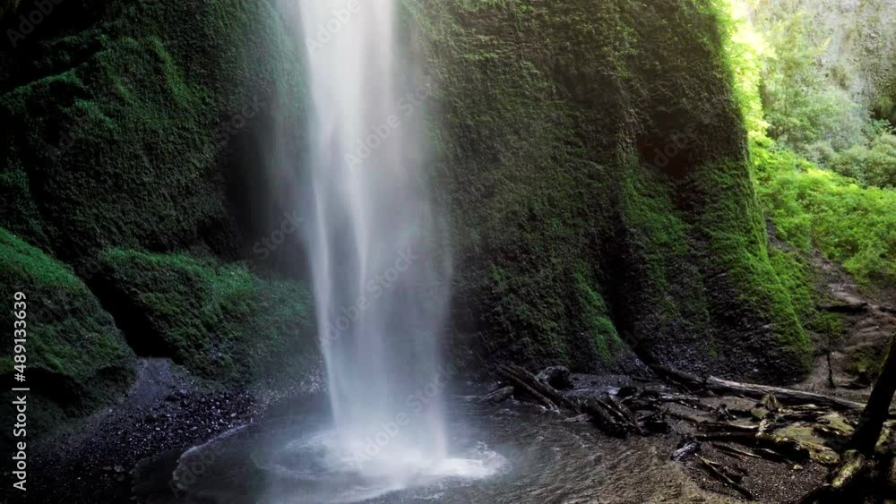 Handheld of hidden Mili Mili misty waterfall streaming into natural pond surrounded by dense green vegetation, Coñaripe, Chile Handheld of hidden Mili Mili misty waterfall streaming into natural pond surrounded by dense green vegetation, Coñaripe, Chile
