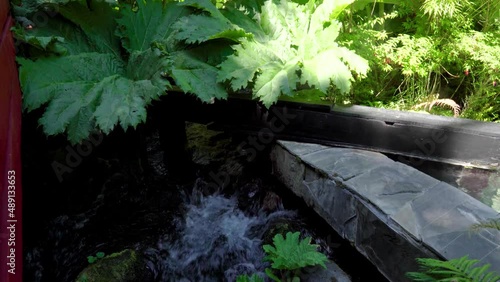 Dolly in of red wooden runway, pools and waterfall in Termas Geometricas hot spring complex, surrounded by woods, Coñaripe, Chile photo