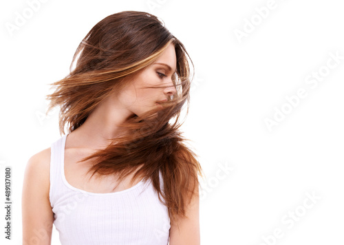 Her hair is filled with body and life. A beautiful young woman swooshing her hair against a white background.