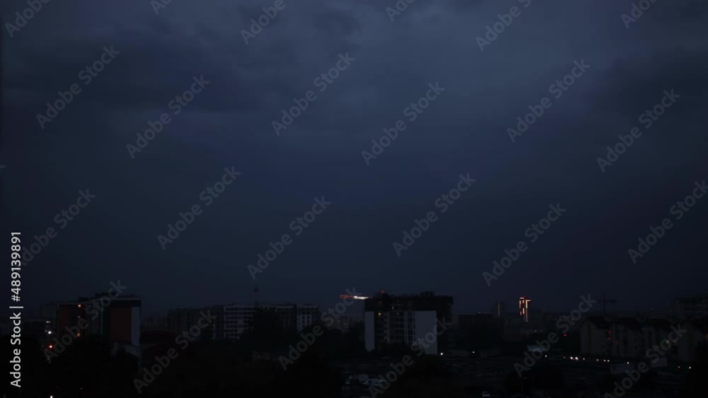Thunderstorms, lightning over city. Flash strikes in stormy night falling on buildings in city. Lightning thunderstorm flashes over the night sky. Low key lighting. Underexposed. Pink light Thunderstorms, lightning over city. Flash strikes in stormy night falling on buildings in city. Lightning thunderstorm flashes over the night sky. Low key lighting. Underexposed. Pink light