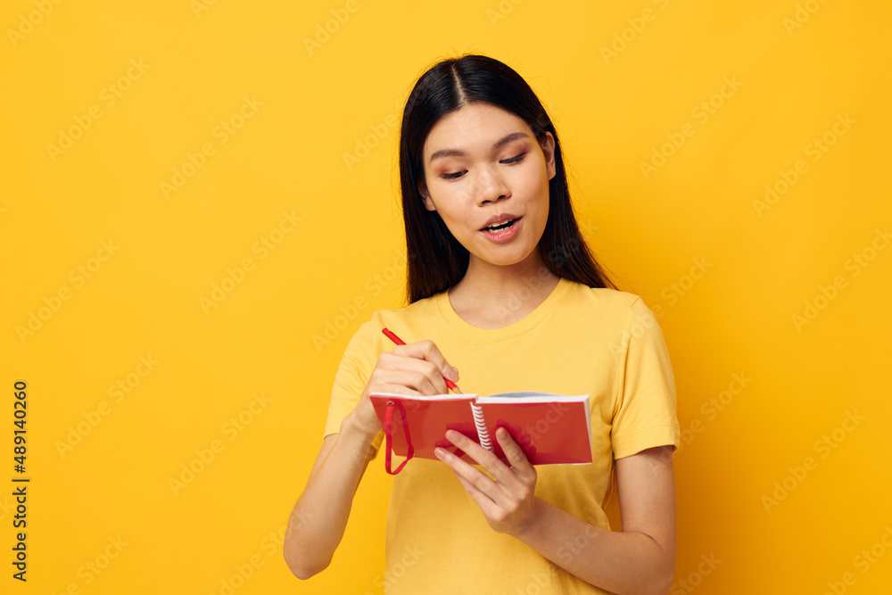 Charming young Asian woman with a notebook and pen in hand isolated background unaltered Charming young Asian woman with a notebook and pen in hand isolated background unaltered