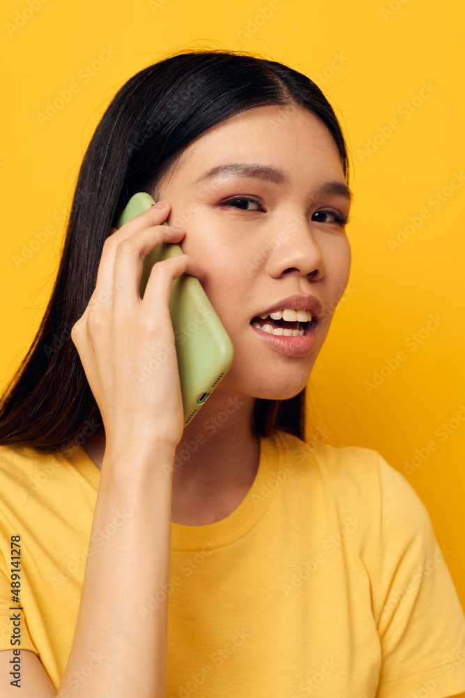 Charming young Asian woman talking on the phone posing technology studio model unaltered Charming young Asian woman talking on the phone posing technology studio model unaltered