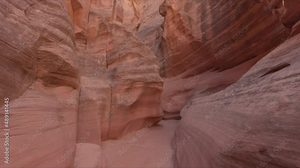 Scenery of the narrow path between sandstone dunes with sun beams above the rocks. Slot canyon with high walls beyond clear blue skyline. High quality 4k footage Scenery of the narrow path between sandstone dunes with sun beams above the rocks. Slot canyon with high walls beyond clear blue skyline. High quality 4k footage