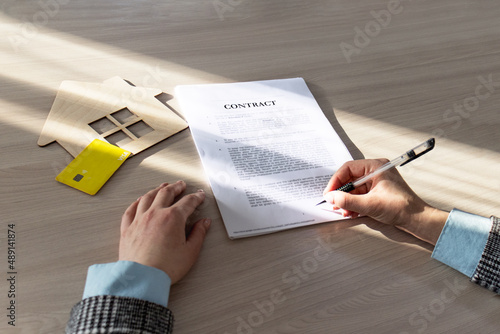 contract for the sale of a house. A woman signs a document to buy a house. Home Mortgage Agreement, Real Estate Concept.symbol, wooden house, contract, sale house, woman, signs, document, buy house,