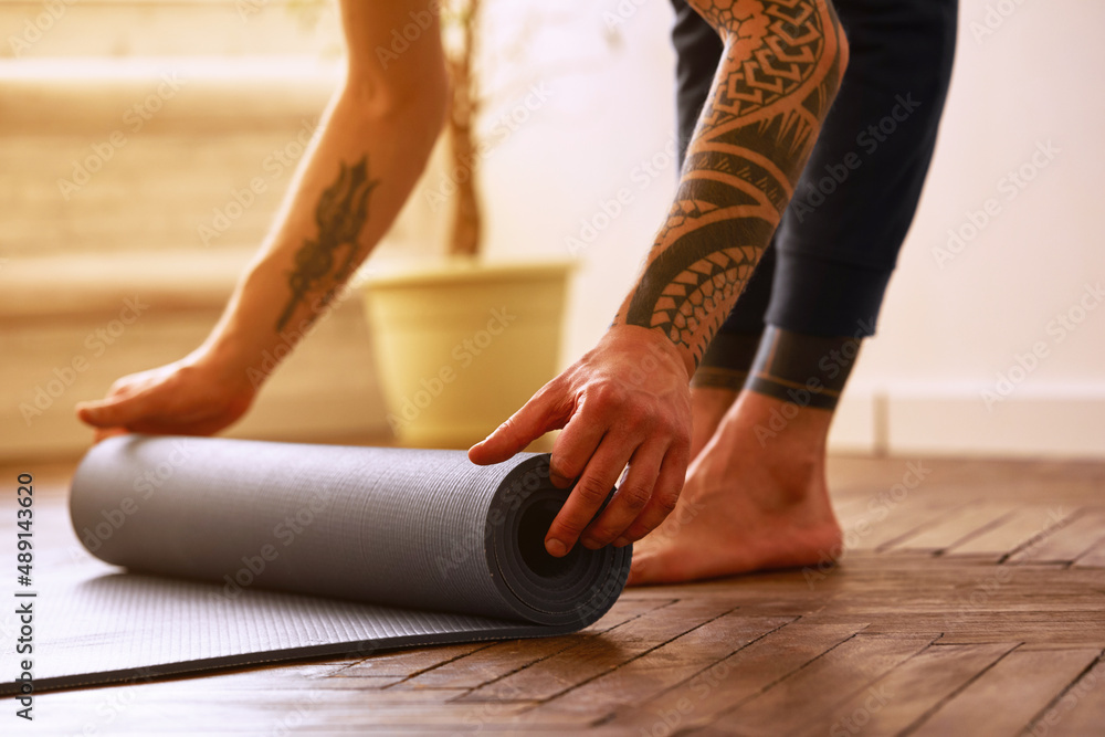 Close-up image of a man with exercise mat preparing for yoga practice