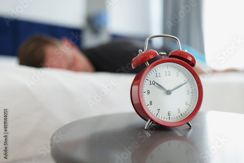 A red alarm clock stands on table in the bedroom