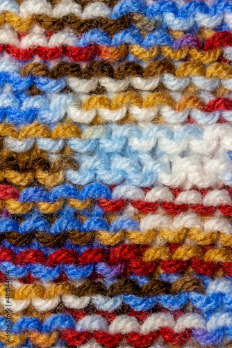 Full frame macro abstract texture background of bright colorful hand-knitted yarn cloth in a simple garter stitch © Cynthia
