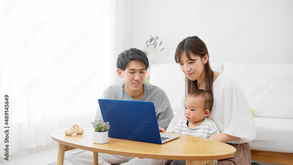 赤ちゃんにノートパソコンを見せる両親 赤ちゃんにノートパソコンを見せる両親