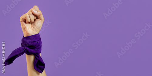 Mano de mujer con señas sobre fondo morado con paleacate o bandana del día de la mujer.  photo