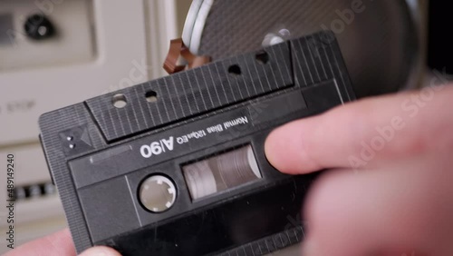 Female Rewinds a Magnetic Tape with Finger on Old Vintage Audio Cassette. Process rewinding a jammed tape manually. Classic black retro cassette 90s for listening to music on a player, tape recorder.