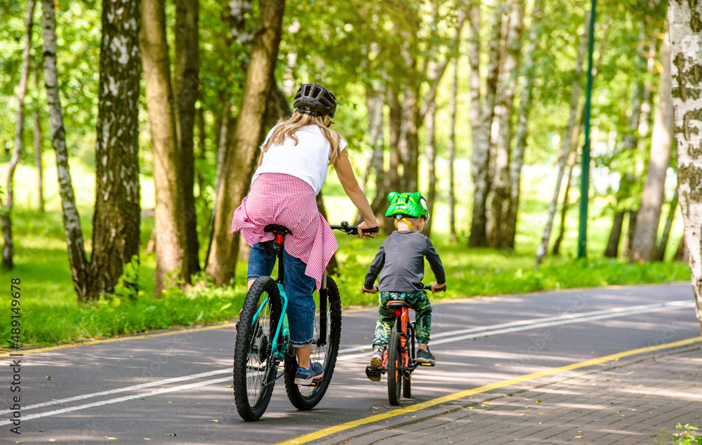 A woman and her son ride bicycles in the park
