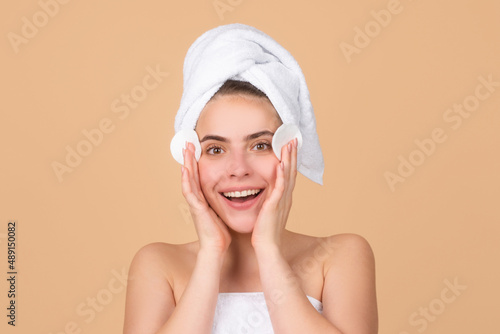 Beauty face portrait. Spa therapy, beautiful woman in towel touching cheek with sponge takes care of skin.
