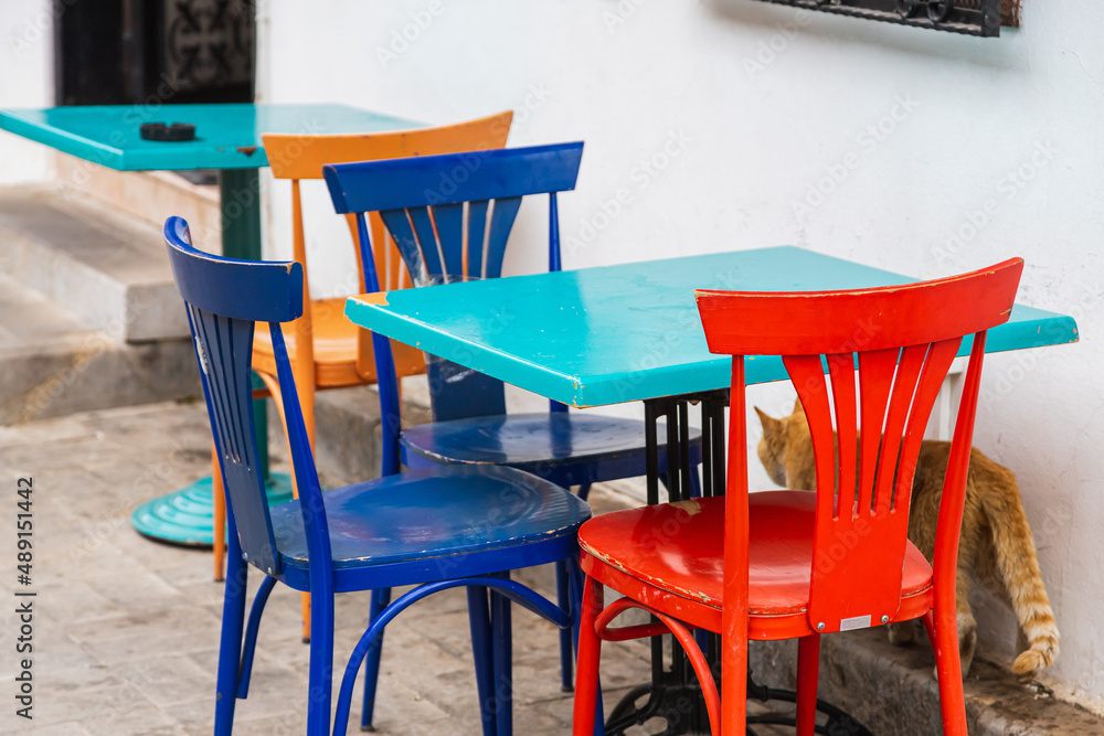 Atmospheric summer photography. Wooden cafe chairs  on table. Outdoor street cafe with colorful wooden chairs
