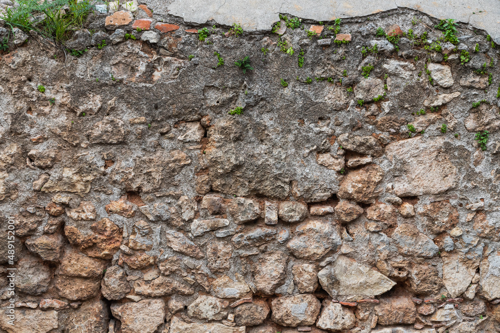 Background of brown-gray stone wall with leaves and moss . Pattern of slate wall texture and background Background of brown-gray stone wall with leaves and moss . Pattern of slate wall texture and background