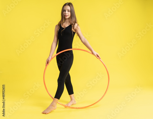 girl gymnast studio. little gymnast trains, shows a gymnastic element. do sport. Isolated on a colored yellow background. Young girl gymnast
