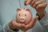 Women's hands hold a piggy bank close-up. Saving and accumulating money, financial security, budget planning and investment.