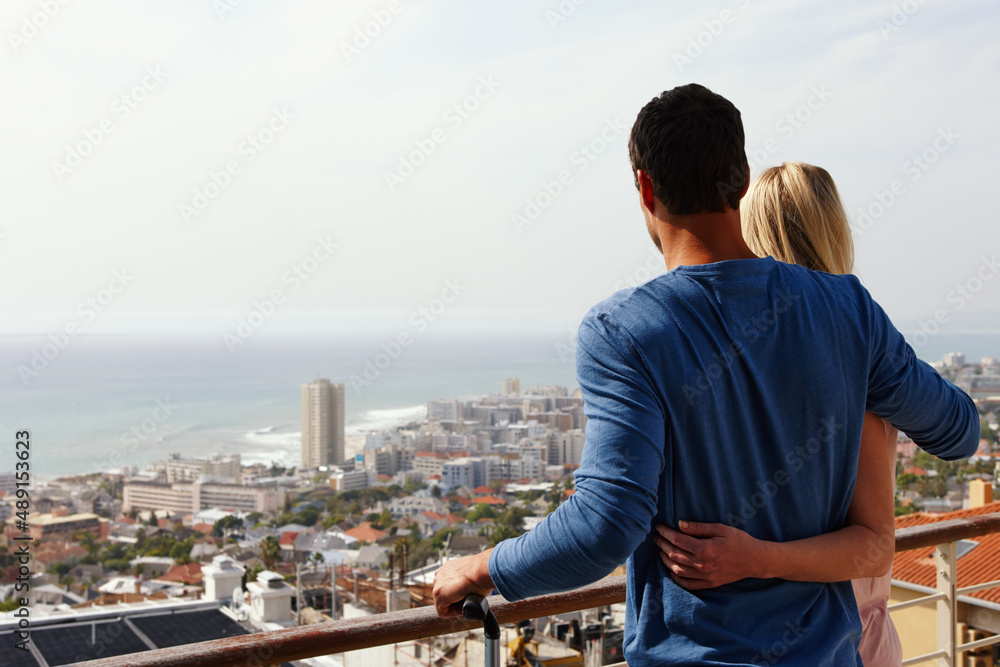 We love our new place. A happy couple standing on a balcony looking over the view.