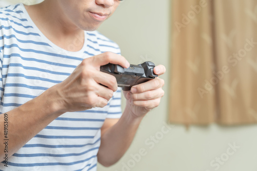 Close up hands of man, gamer using gaming controller or game pad when play video console game or online computer game at home.Gaming is relaxing from stressed and making friend, creativity, knowledge.