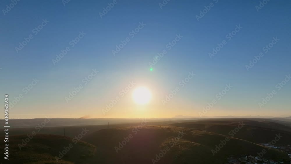 Drone descending with sun lowering over hills