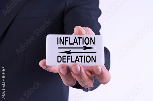 businessman holding banner with inflation and deflation concept