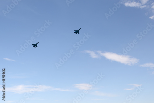 Two combat aircraft against a blue sky with clouds.