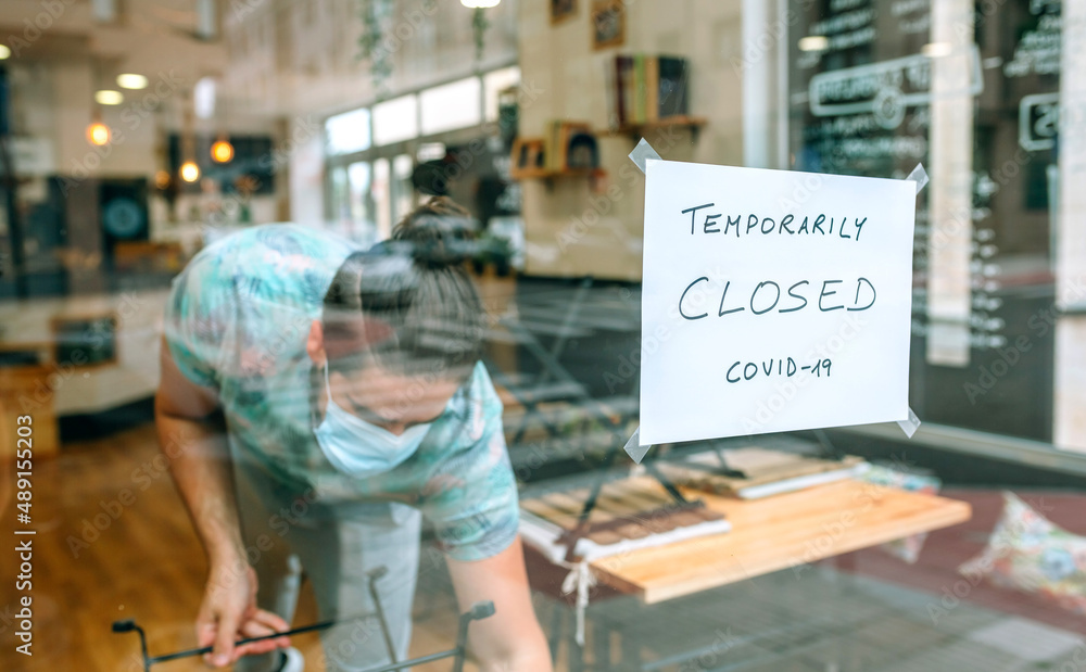 Man with a mask working behind the glass of his restaurant closed by covid-19 Man with a mask working behind the glass of his restaurant closed by covid-19