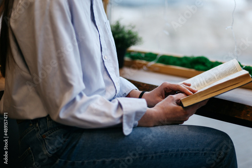 brunette girl in a cafe drinking coffee, reading a book, close up 