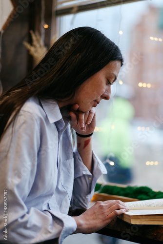 brunette girl in a cafe drinking coffee, reading a book  © Alexandra