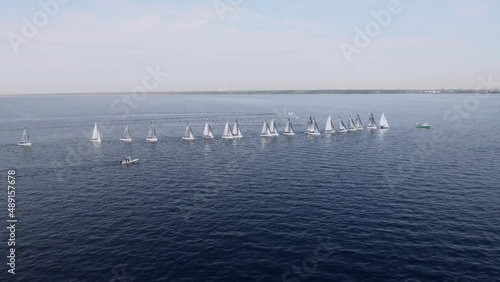 Sailing yachts lined up in the sea during a sailing regatta and cast shadows