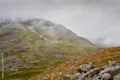 The cloud covered rocky mountain summit of Scafell Pike from the top of Lingmell in the English Lake District, UK.