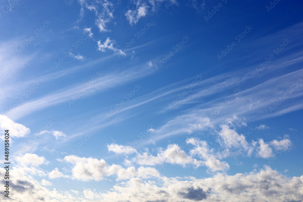 Obraz premium Blue sky covered with white cumulus and cirrus clouds. Spring cloudscape, beautiful weather background