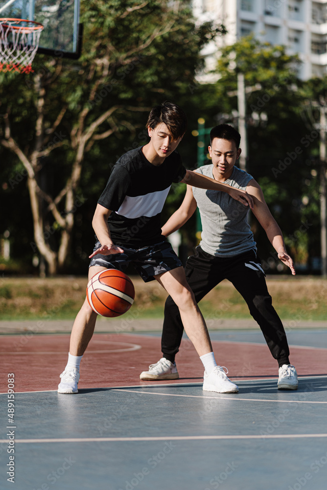Sports and recreation concept two male basketball players enjoying playing basketball together on the sports ground