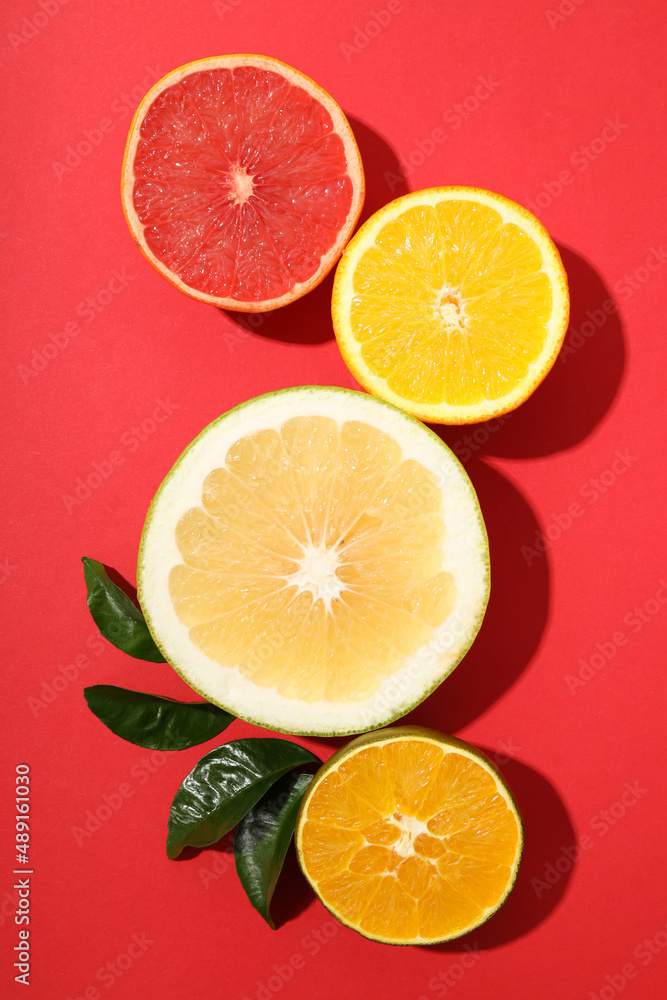 Citrus fruits halves with leaves on red background