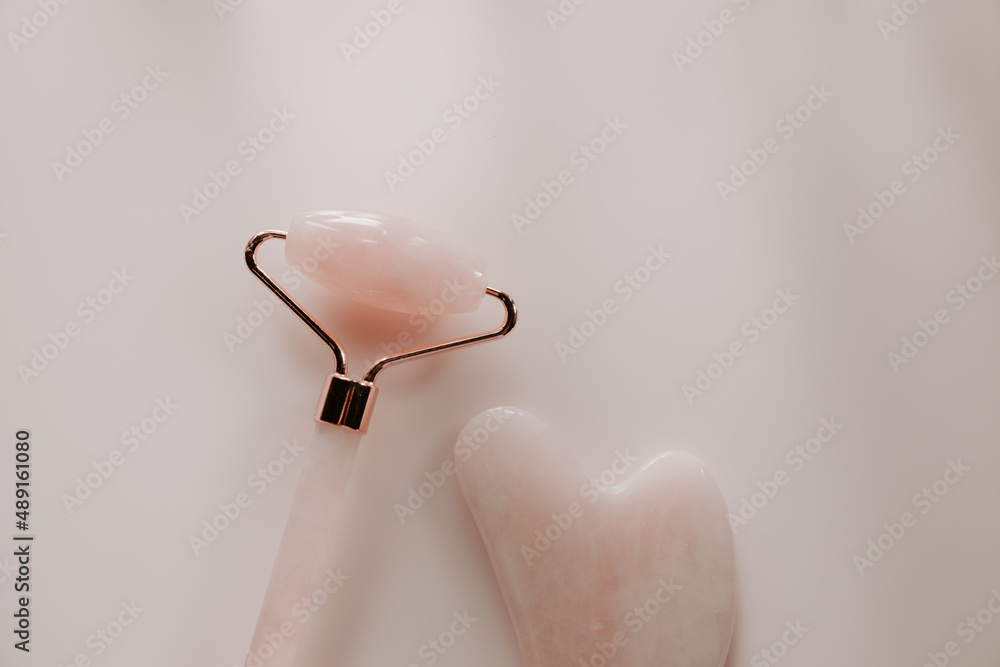 Pink gua sha and quartz face massage roller close-up