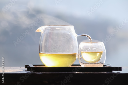 Morning cup of hot tea with lake background at sunrise.