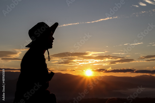 silhouette Young woman traveler looking at sunrise over the mountain.