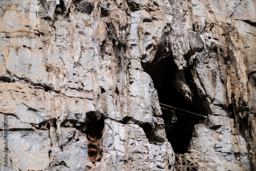 Bat cave entrance on cliff of rock mountain.