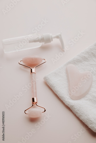 Skin care concept. Jade face roller for beauty facial massage therapy and guasha with towel. Vertical image