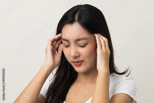 Young asian beautiful woman hand touching head she's feeling depressed stress headache be tired from working standing on isolated white background she has symptom office syndrome. © Chanakon